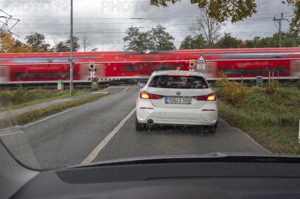 Regional train crosses a restricted level crossing, cars waiting in front of it, Fürth Mittelfranken, Bavaria, Germany