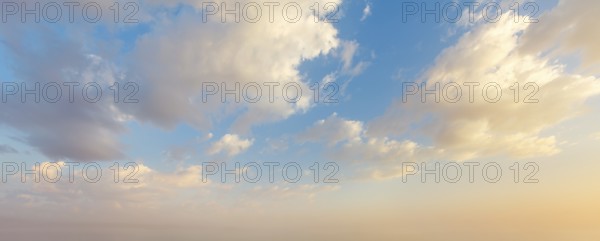 Colorful sunset sky showcases vibrant hues and fluffy clouds as day transitions into night, creating a beautiful and serene scene
