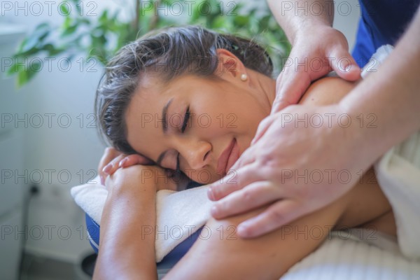 A woman enjoys a soothing back massage by a professional therapist using oil in a serene spa salon focused on relaxation and wellness