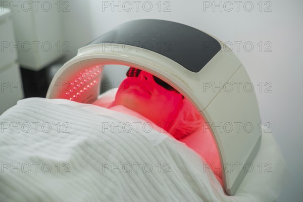 Client undergoes facial cleansing with LED light therapy to target acne while protected by goggles and a hair cap for comfort