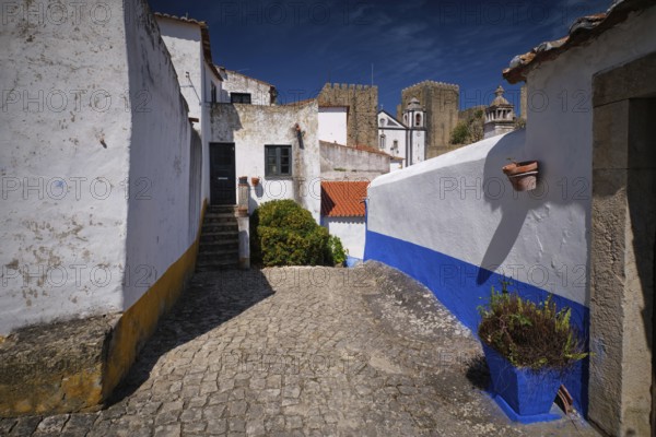Historic streets of Obidos, Portugal, surrounded by white houses and stone walls under a clear blue sky