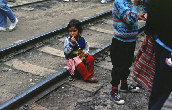 Little girl sitting on railroad tracks, Agua Caliente, Andean Highlands, Peru, South America, September 1997, vintage, retro, old, historic
