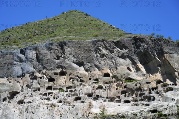 A steep mountain with numerous caves under a clear blue sky, cave town, cave monastery, Vardzia, Samtskhe—Javakheti region, Samtske Javacheti, Lesser Caucasus, Georgia