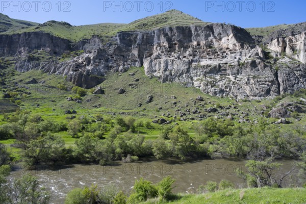 Rocky cliffs and flowing river in a green setting. Picturesque scenery, Kura river, cave monastery, Vardzia, Vardzia, Samtskhe—Javakheti region, Samtske Javacheti, Lesser Caucasus, Georgia