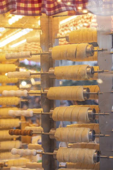 The trendy Chimney Cake stand at Stuttgart Christmas Market offers freshly baked, sweet treats. The aromatic scents attract numerous market visitors who enjoy the unique dessert
