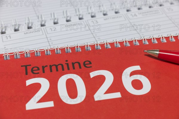 Red 2026 calendar with spiral binding and a red pen, diary