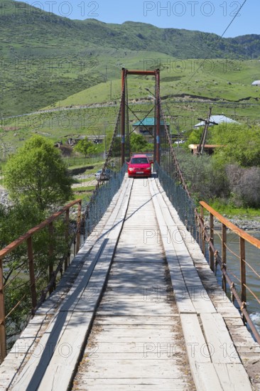 A car drives across a wooden suspension bridge in green surroundings, Kura River near Nijgori, Samtskhe-Javakheti region, Samtskhe-Javakheti, Georgia