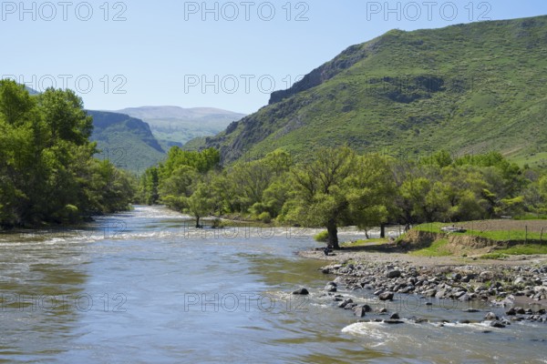 A wide river flows through lush green countryside surrounded by high hills and clear skies, Kura River near Nijgori, Samtskhe-Javakheti region, Samtskhe-Javakheti, Georgia