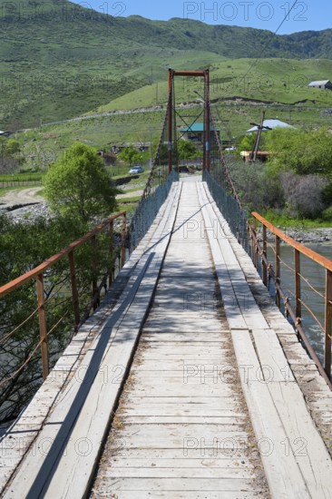 A wooden suspension bridge stretches across a river with a green landscape, Kura River near Nijgori, Samtskhe-Javakheti region, Samtskhe-Javakheti, Georgia