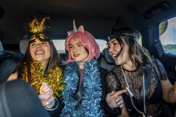 Young women friends celebrating new year's eve in costume, laughing and carefree in the back seat of a car, enjoying a festive night out road trip party atmosphere