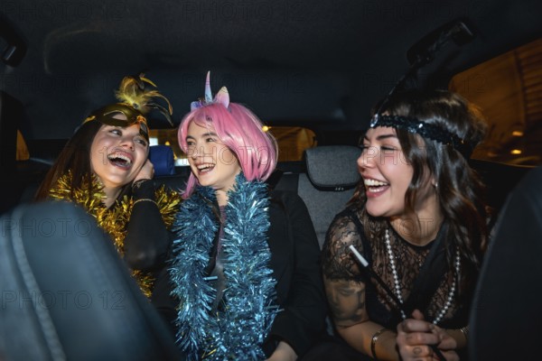 Young women sitting in the back seat of a car, wearing festive costumes and garlands, sharing a joyful moment and laughing together during a night out for a special celebration