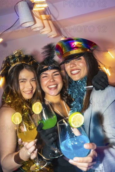 Three happy young women celebrating new year's eve, wearing festive costumes and holding colorful drinks with lime garnishes in a lively, vibrant party atmosphere