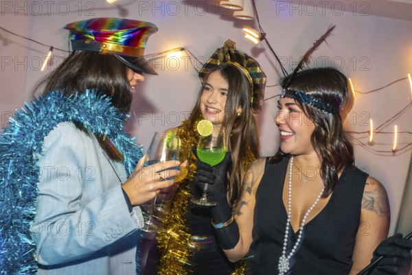 Three happy young women enjoying a festive new year's eve or costume party with drinks and tinsel decorations, sharing smiles and creating joyful celebration moments together