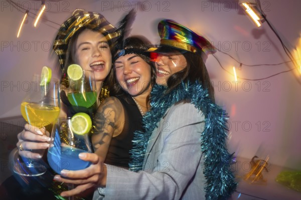 Three happy young women in festive costumes laughing and cheering with vibrant cocktails, enjoying a fun celebration together in a lively party atmosphere