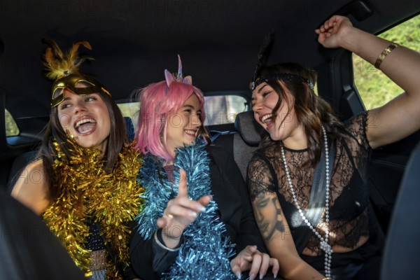 Young happy women dressed in costumes and festive garlands celebrating, laughing, and having fun during a party while sitting in the backseat of a car