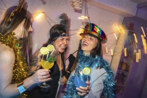 Young women friends enjoying a festive costume party at home, laughing and holding refreshing cocktails, celebrating the holiday season together in a joyful atmosphere