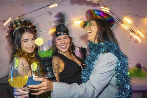 Three smiling young friends wearing party costumes and festive accessories celebrating a special occasion with vibrant drinks, enjoying a cheerful night out or a joyous gathering