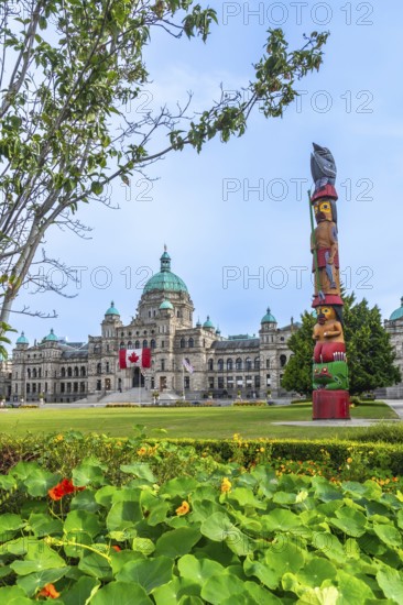 Vibrant totem pole proudly positioned in front of the majestic parliament buildings in victoria, british columbia, highlighting the region's rich cultural heritage on a sunny summer day