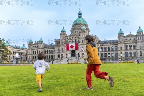 Mother and son running on the lawn in front of the british columbia parliament buildings in victoria, british columbia, canada, enjoying a summer day
