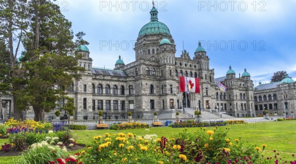The british columbia parliament buildings stand majestically in victoria, surrounded by vibrant flower gardens, creating a picturesque scene on a sunny summer day