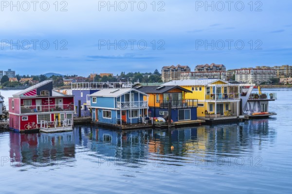 Fisherman's wharf park's vibrant floating homes create a picturesque scene reflecting in the calm waters of victoria, british columbia, under a serene blue sky