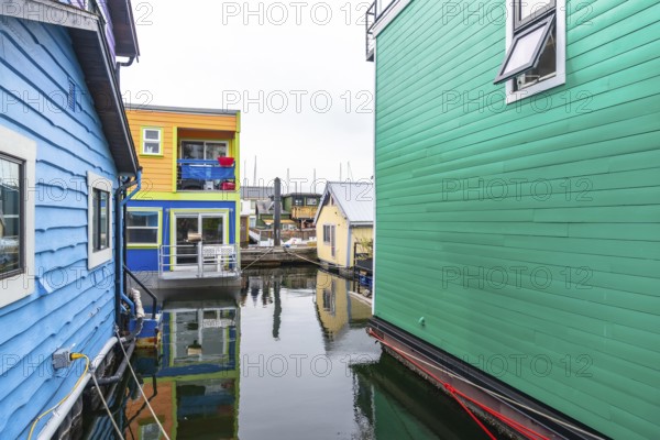 Fisherman's wharf park in victoria, british columbia, features vibrant floating homes reflecting in calm waters, creating a picturesque scene of this unique community