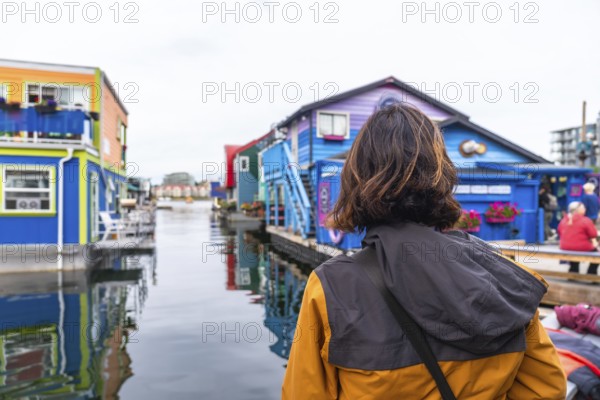 Tourist observing the colorful floating houses of fisherman's wharf park in victoria. British columbia. Canada. A popular tourist destination known for its vibrant atmosphere and unique architecture