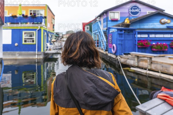 Tourist admiring the colorful floating houses of fisherman's wharf park, a popular tourist destination in victoria, british columbia, canada, during a sunny summer day