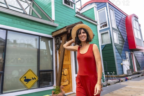 Happy tourist walking through fisherman's wharf park, enjoying a sunny summer day among vibrant, colorful floating houses in victoria, british columbias charming waterfront community