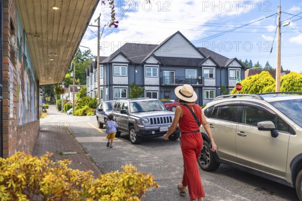 Tourists are walking along a street with parked cars in chemainus, a town known for its outdoor murals, located on vancouver island, british columbia, canada