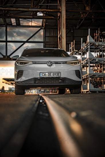 White car in front of warehouse structure at sunset on rails, VW ID4 electric car, Deer Carsharing, Calw, Germany