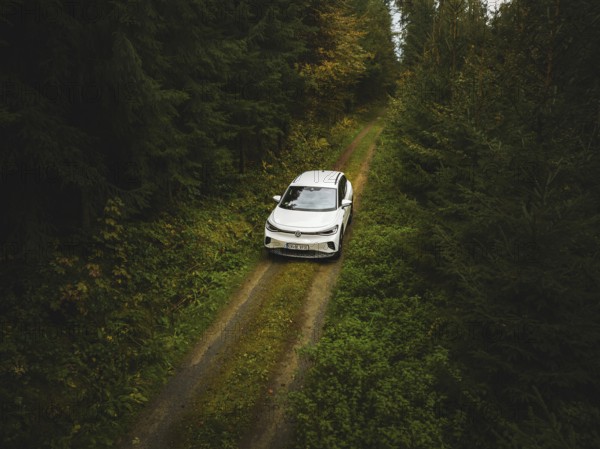 A white Volkswagen photographed from above on a green forest path, VW ID4 electric car, Deer Carsharing, Calw, Germany
