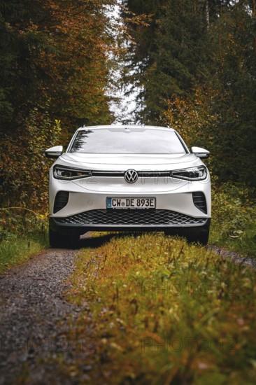White car on a forest road in autumn surroundings, VW ID4 electric car, Deer Carsharing, Calw, Germany