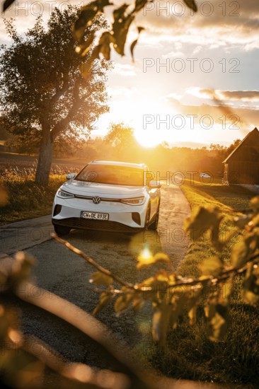 White car on a country road at sunset with silhouettes, VW ID4 electric car, Deer Carsharing, Calw, Germany