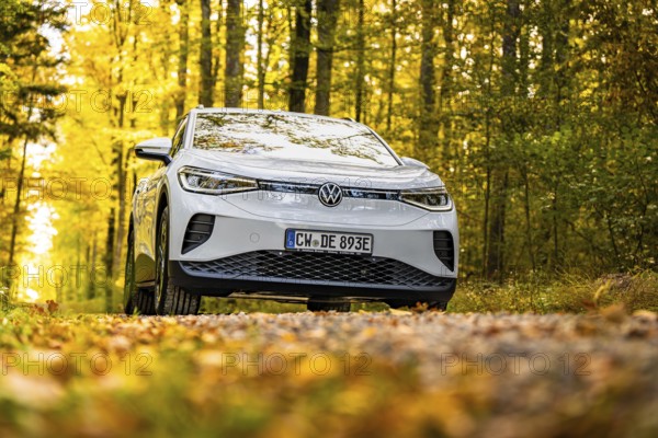 Front view of a white car on a forest road in autumn, VW ID4 electric car, Deer Carsharing, Calw, Germany