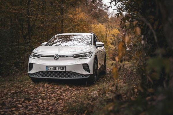 A white Volkswagen in autumn forest with lots of leaves, VW ID4 electric car, Deer Carsharing, Calw, Germany