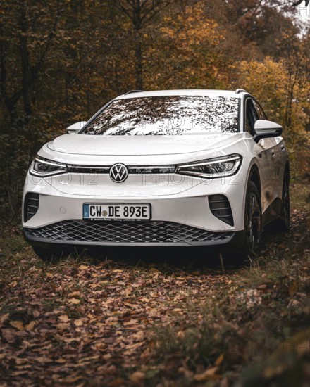 A white Volkswagen surrounded by autumn leaves in the forest, VW ID4 electric car, Deer Carsharing, Calw, Germany