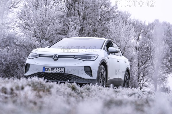 A white car is parked in a frosty winter landscape with snow-covered trees, VW ID4 electric car, deer car sharing, Calw, Germany