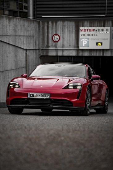 Red Porsche Taycan stands in front of a modern building on paved area, Porsche Taycan, Deer Carsharing, Calw, Germany