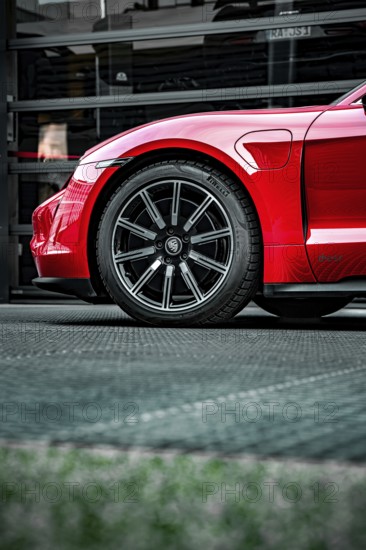 Side view of the front wheel of a red Porsche, focus on rim and body, Porsche Taycan, Deer Carsharing, Calw, Germany