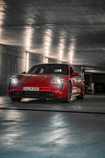 Red Porsche Taycan parked in an illuminated underground car park with an urban atmosphere, Porsche Taycan, Deer Carsharing, Calw, Germany