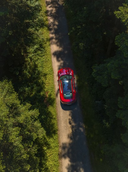 Bird's eye view of red sports car on a forest road, Porsche Taycan, Deer Carsharing, Calw, Germany
