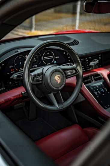 Modern car interior with red and black interior, showing steering wheel and instruments, Porsche Taycan, Deer Carsharing, Calw, Germany