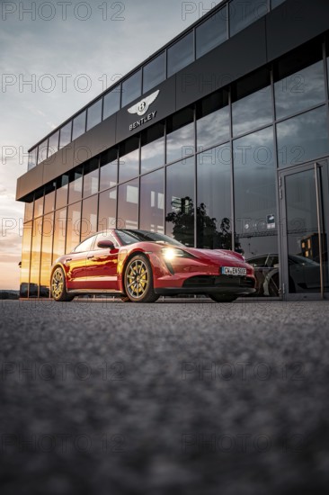 Red sports car in front of a Bentley building at sunset, Porsche Taycan, Deer Carsharing, Calw, Germany