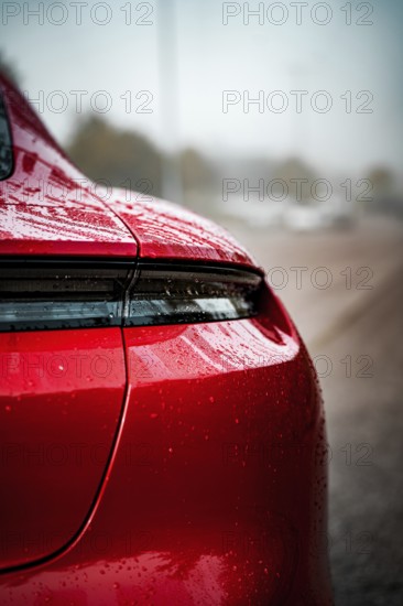 Close-up of a red Porsche with wet body and shiny rear light, Porsche Taycan, Deer Carsharing, Calw, Germany