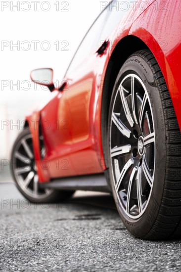 Side view of a red vehicle focusing on the front wheel, Porsche Taycan, Deer Carsharing, Calw, Germany