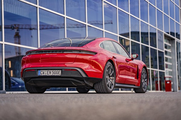 Red car in front of modern architecture with glass facades in the city, Porsche Taycan, Deer car sharing. Calw, Germany