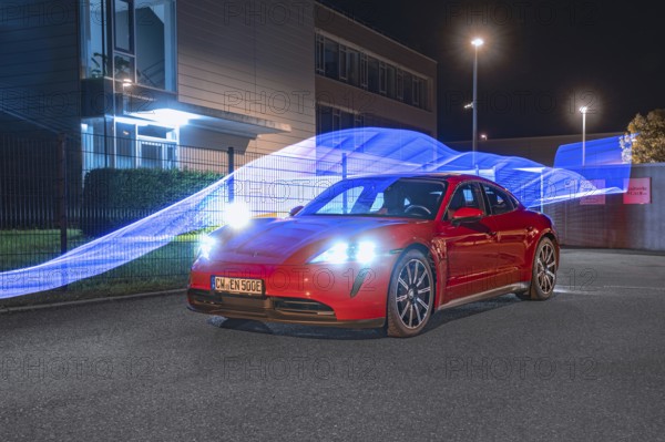 Red car at night with light strips in the background, Porsche Taycan, deer car sharing. Calw, Germany