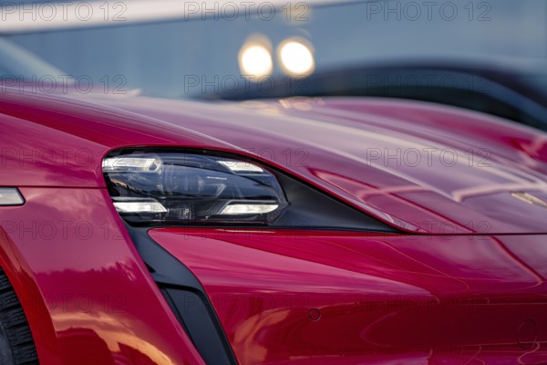 Close-up of red car front with modern headlights and reflections, Porsche Taycan, deer car sharing. Calw, Germany