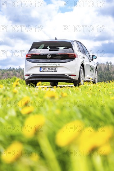 A white car is parked in a meadow, photographed from the rear view, ID3 VW, Deer Carsharing. Calw, Germany